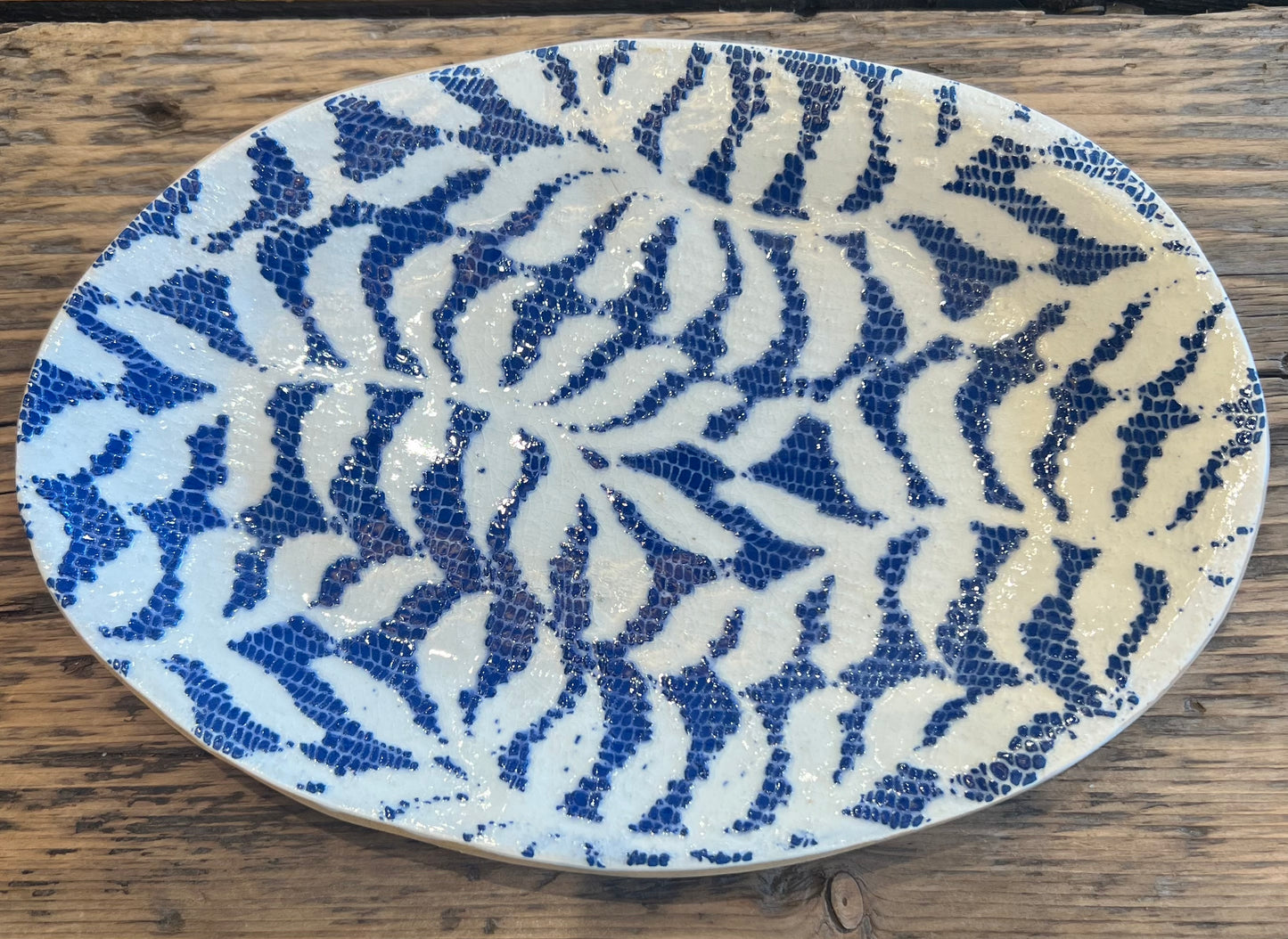 Mosaic plate with blue and white pattern on a wooden surface